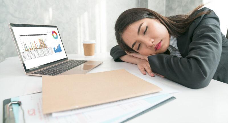 Overworked And Tired Businesswoman Sleeping Over A Laptop In A Desk At Work In Her Office